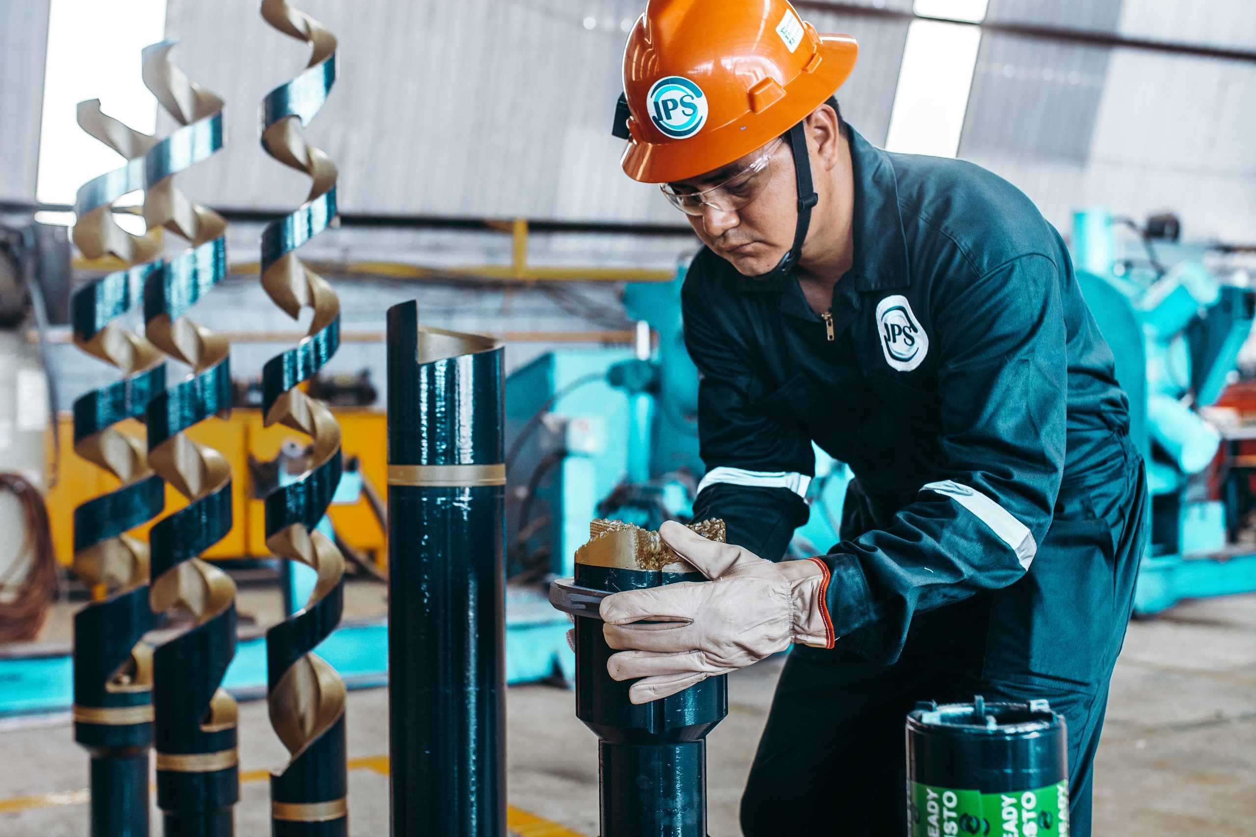 Technician in an orange hard hat inspecting a drill bit