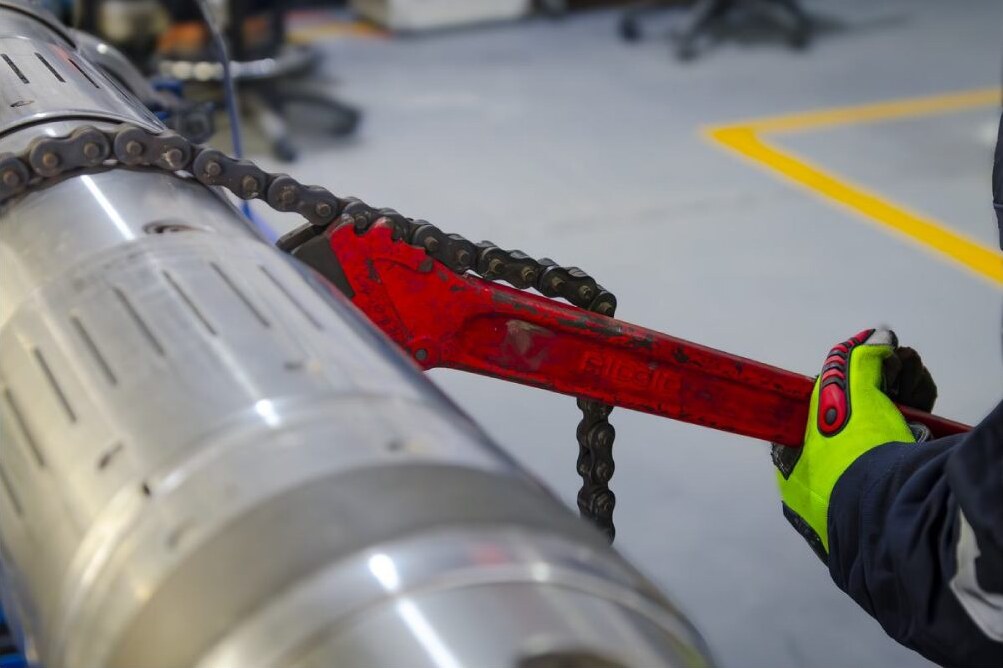 Wellbore cleaning tool being adjusted with a chain wrench