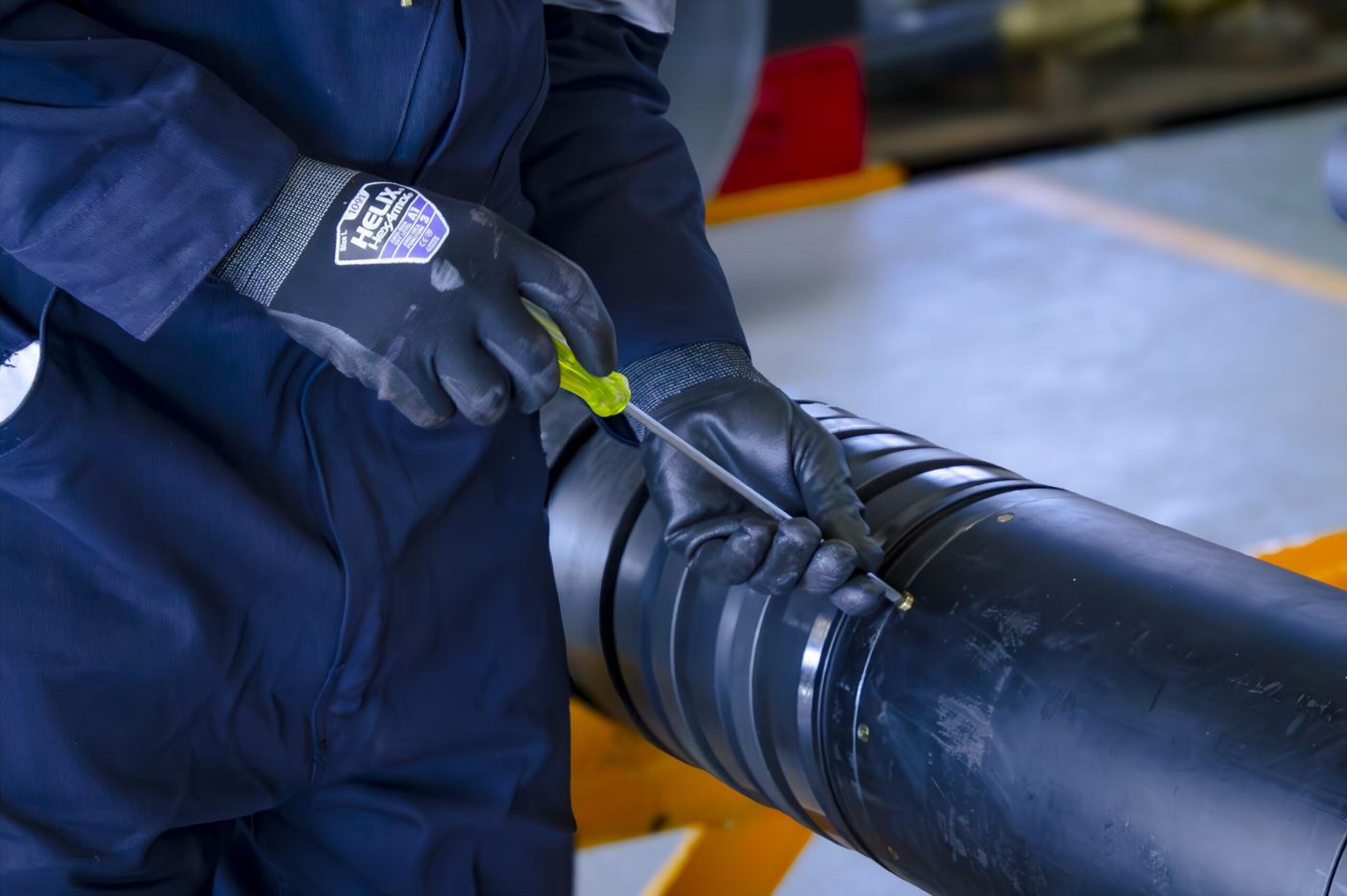 Gloved hands adjusting a pipe cutting tool