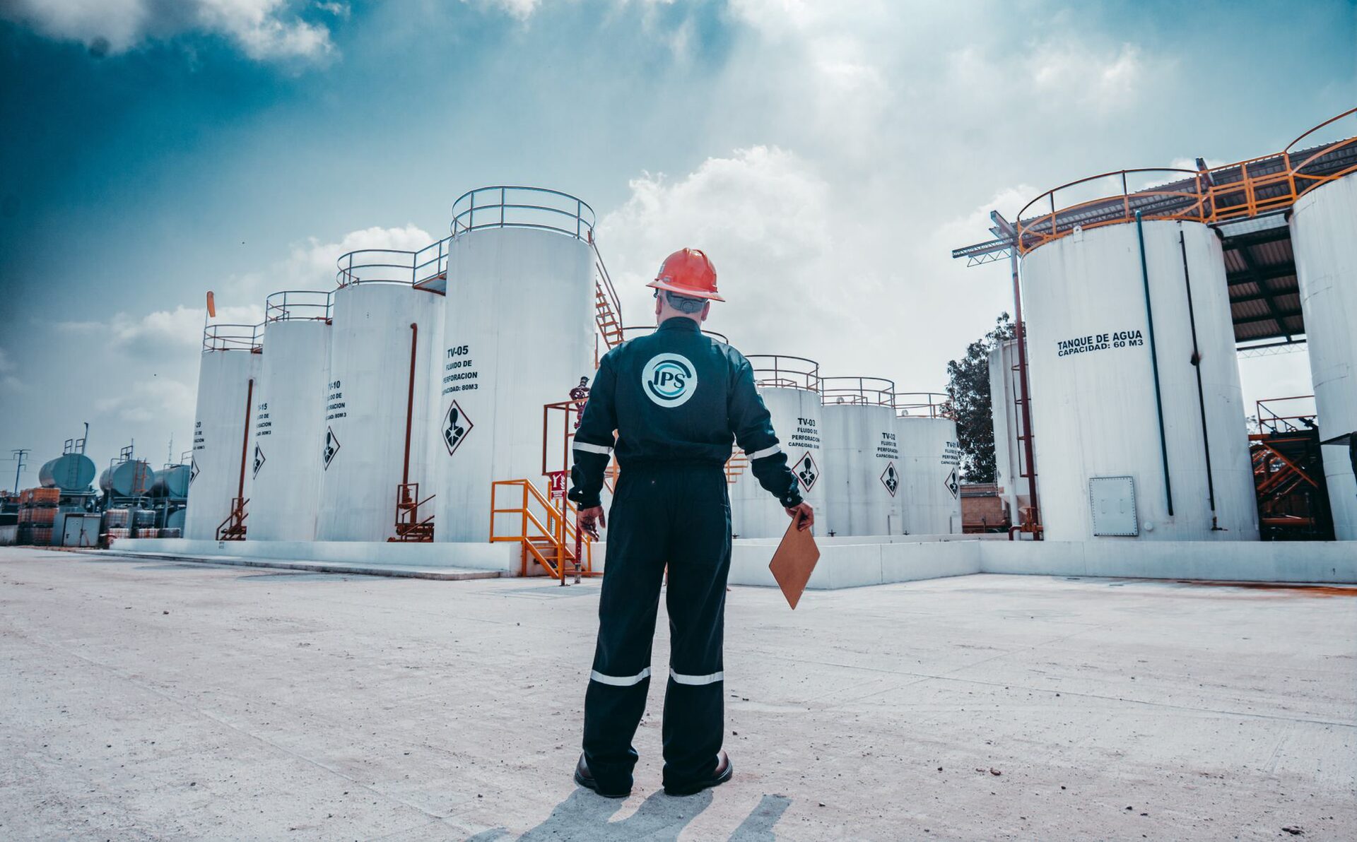 Field engineer walking towards fluid storage tanks