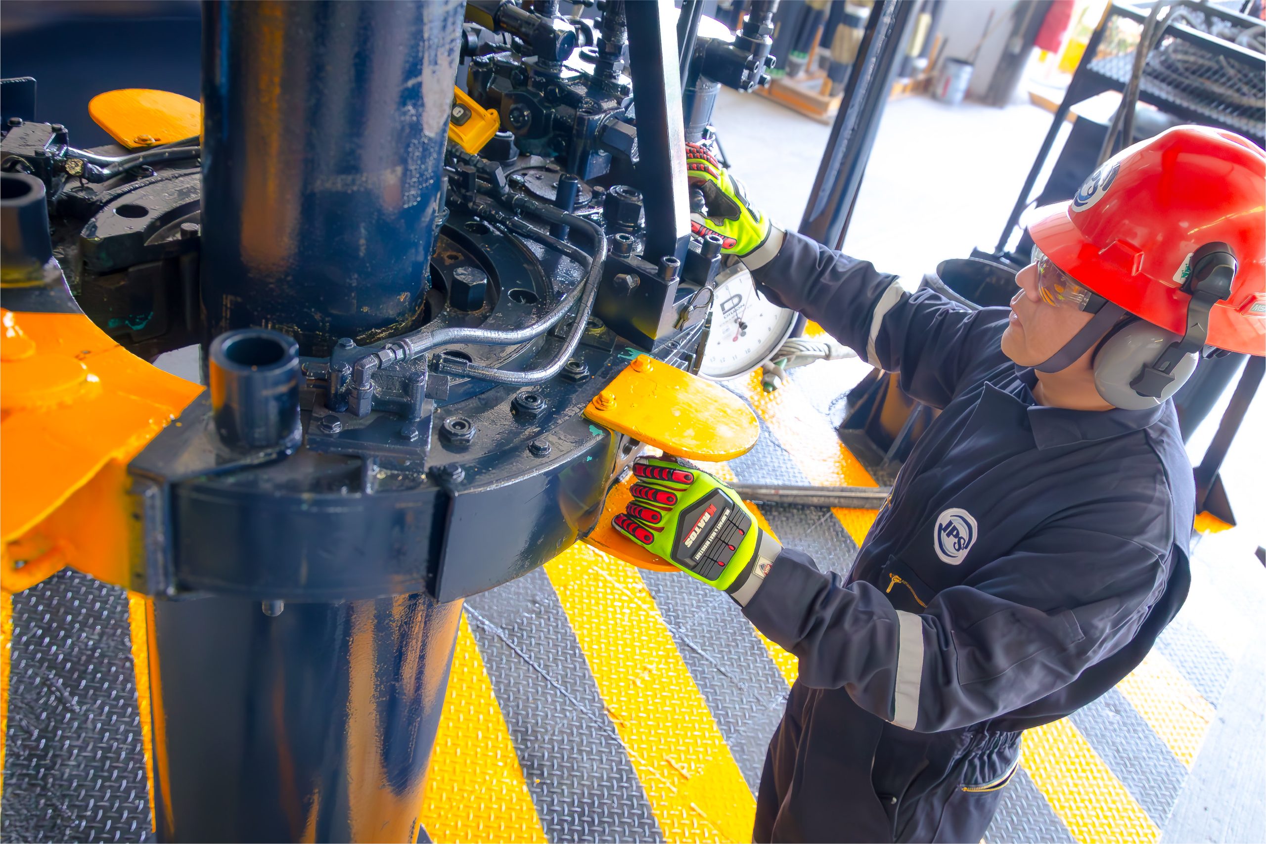 Technician in a red hard hat working on heavy equipment