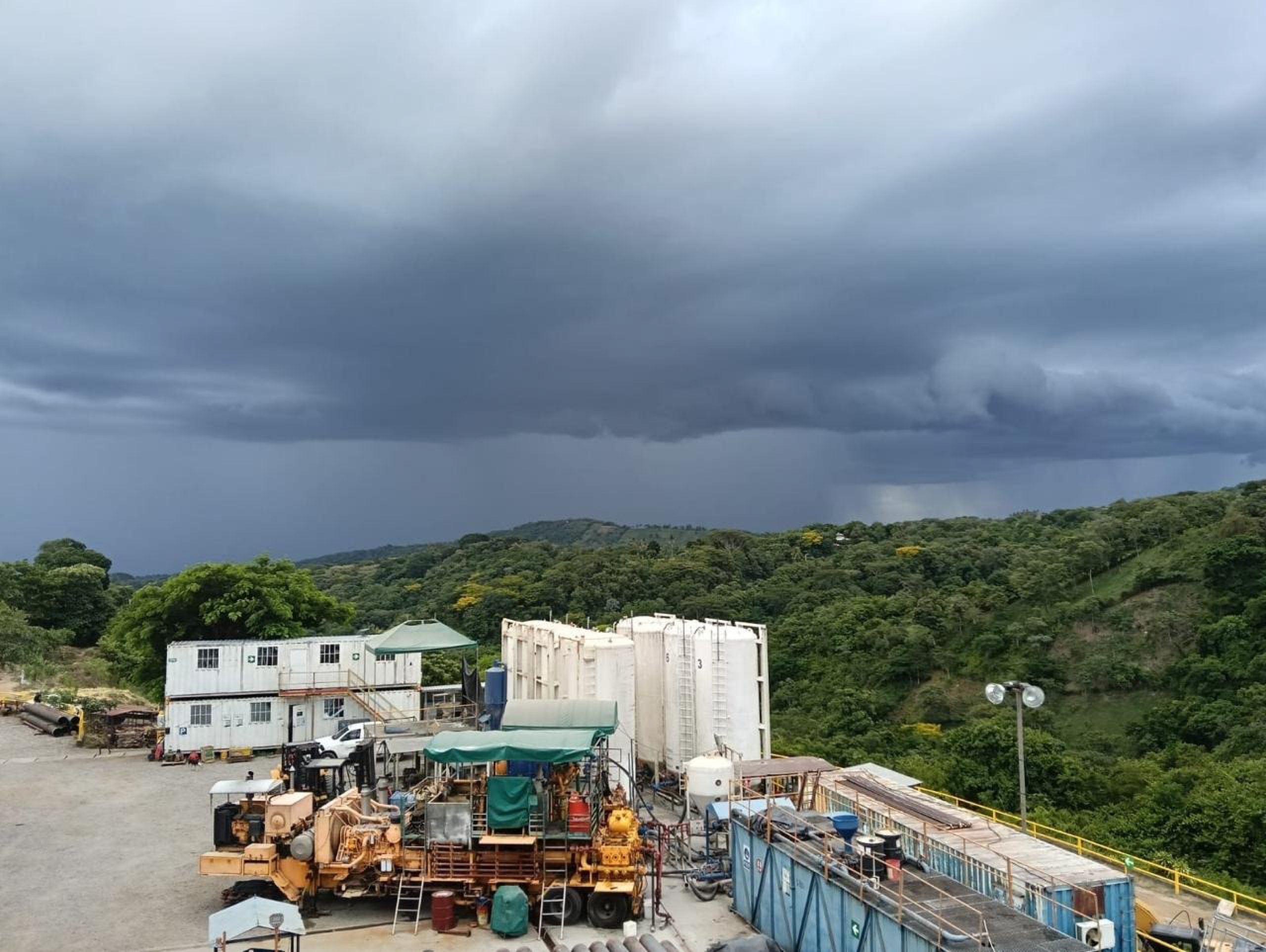 Geothermal facility among forested hills under a stormy sky