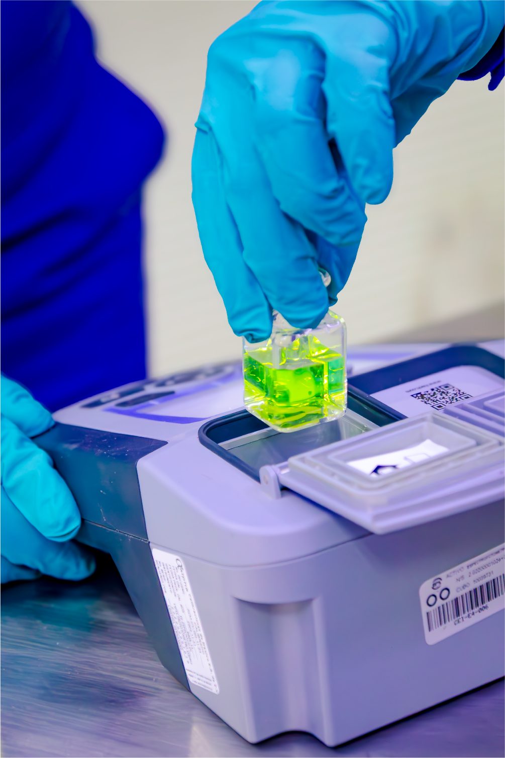 Gloved hand placing a sample cell in a laboratory analyzer